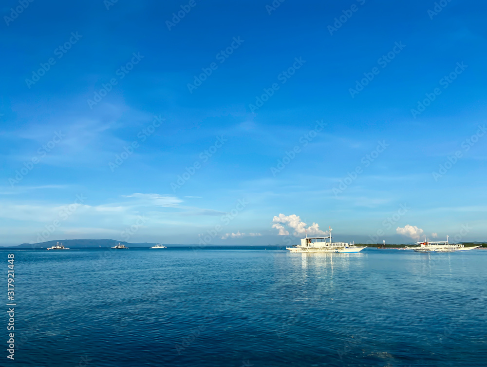 Monochrome beautiful landscape of blue sky and calm sea. Boats and ships drift in the ocean on the horizon against the background of white clouds