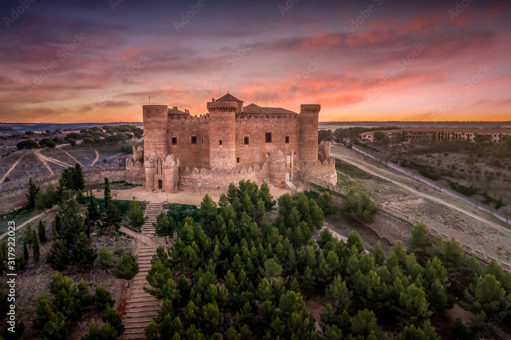 Aerial view of Belmonte castle in Cuenca Spain with circular walls, six towers and tower of homage, brick facade gallery and castle gates with dramatic sunset sky