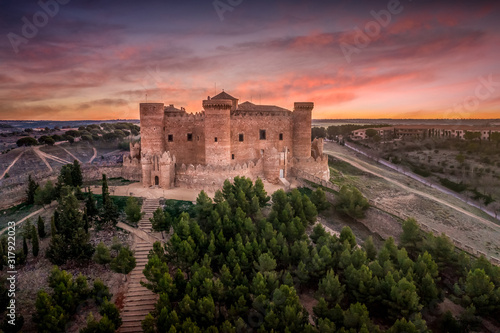 Aerial view of Belmonte castle in Cuenca Spain with circular walls, six towers and tower of homage, brick facade gallery and castle gates with dramatic sunset sky