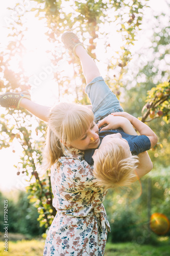 Young Woman Mother Hugging Her Baby Son In Sunny Garden. Outdoor Summer Portrait