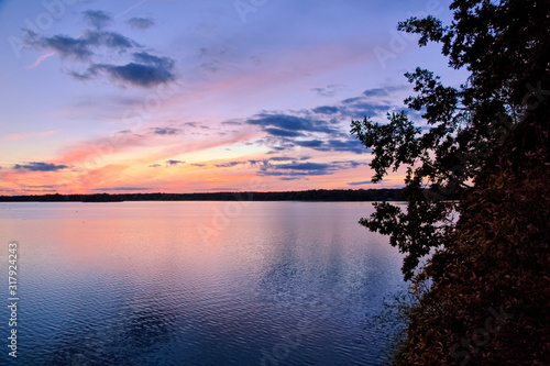 View of the lake at sunset with picturesque play of colors, silhouettes and a peaceful atmosphere.