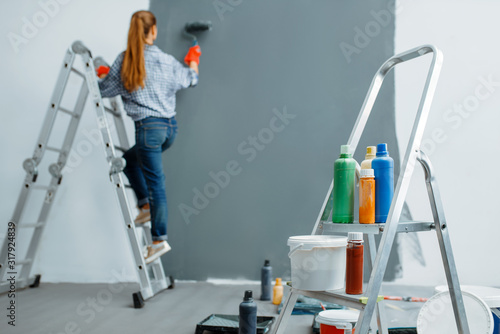 Female house painter paints walls indoor
