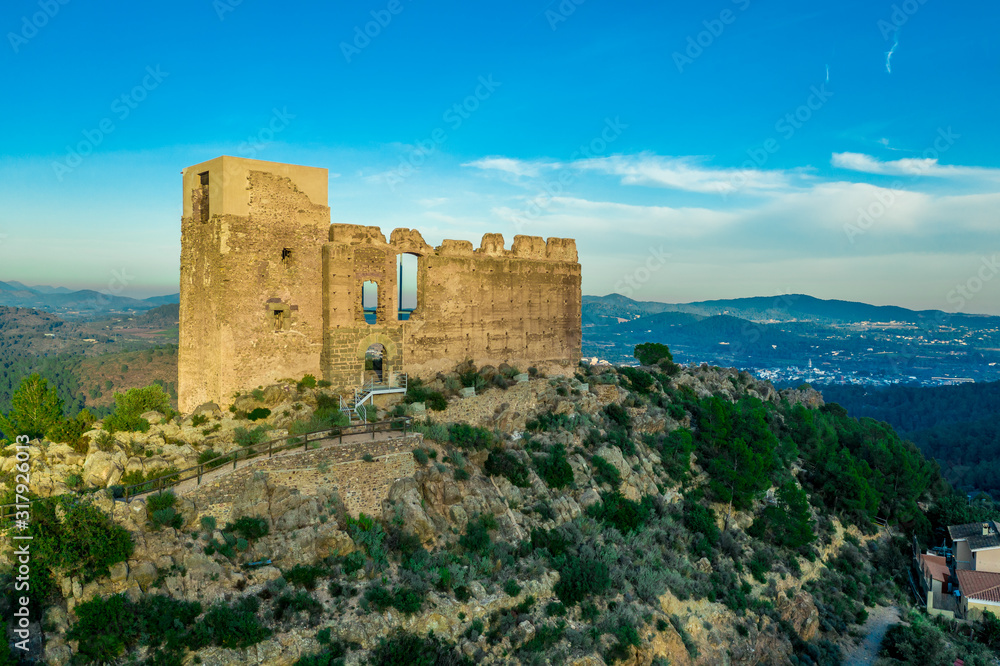 Aerial view of ancient ruined Gothic Beselga castle above the Peniscola Morella road with half restored keep tower and palace building supported by steel beams during sunset