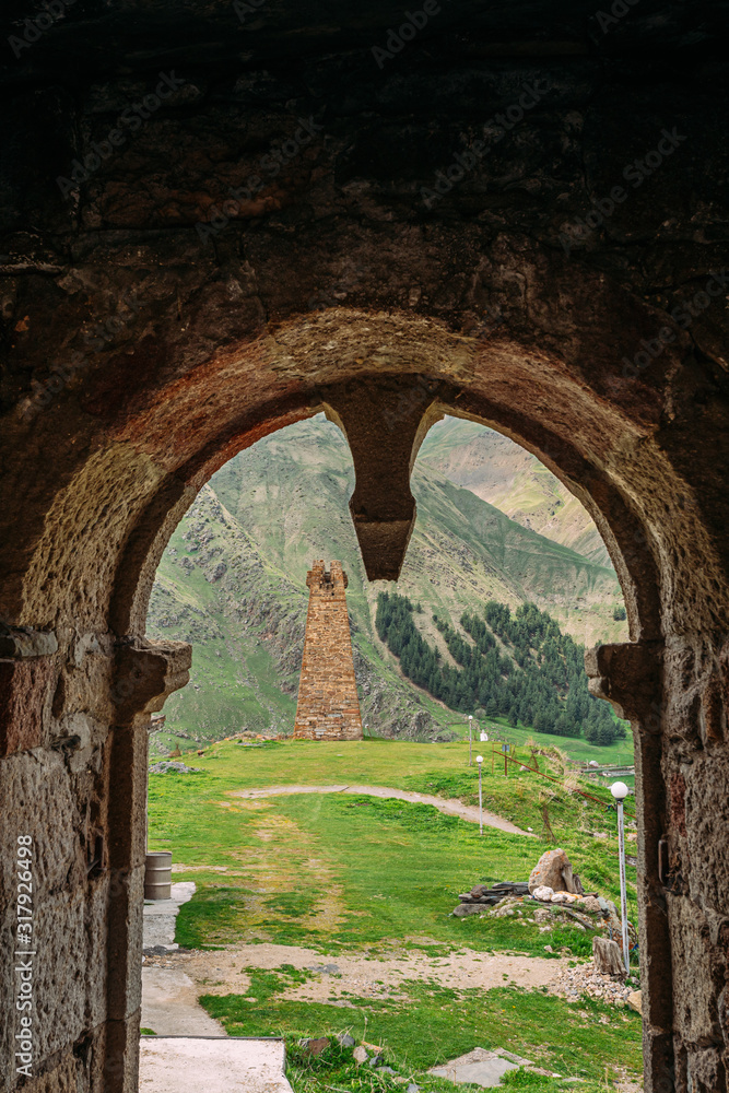Sioni, Georgia. Ancient Old Stone Watchtower On Mountain Background In Sioni Village, Kazbegi District, Mtskheta-Mtianeti Region, Georgia. Spring Or Summer Season. Famous Landmarks And Places In