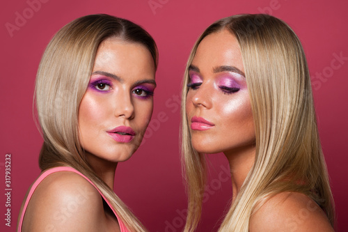Fashion portrait of pretty blonde women fashion models with bright pink makeup on pink background