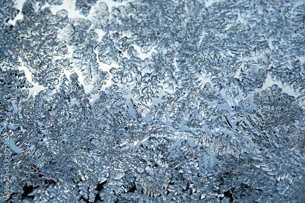 Ice crystals very close up on a window pane in winter. Frozen water. Mystical fabulous abstract pattern. Weather forecast: frost, cooling. Blue background or wallpaper. Strong macro plan Ice crystals very close up on a window pane in winter. Frozen water. Mystical fabulous abstract pattern. Weather forecast: frost, cooling. Blue background or wallpaper. Strong macro plan