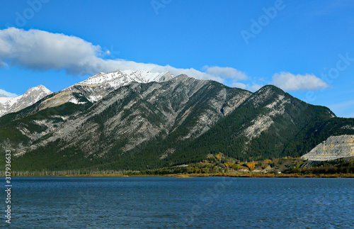 Blue sky with clouds and blue lake with mountains in the background