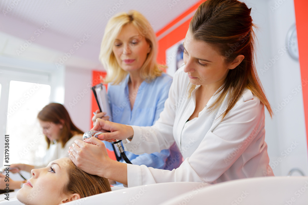 Obraz premium future hairdresser wetting clients hair