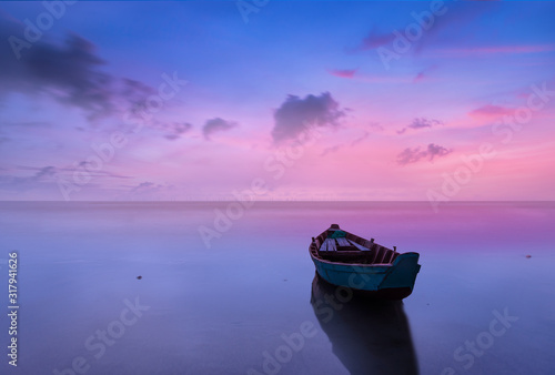 Fotografia Dramitc sunset with boat on beach