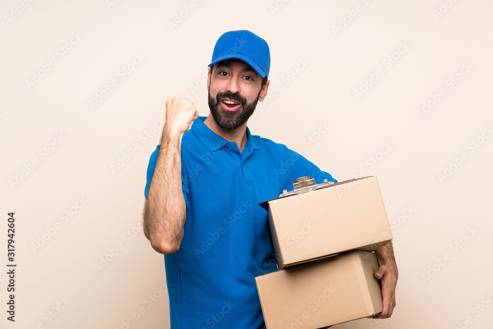 Delivery man with beard over isolated background celebrating a victory in winner position