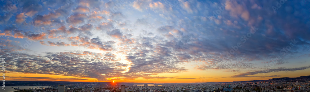Amazing scenic view of the colorful sky with the sun over the city. Panoramic view from a drone.