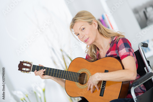 mature woman in wheelchair playing guitar