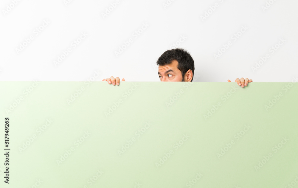 Young handsome man with beard holding a big green empty placard