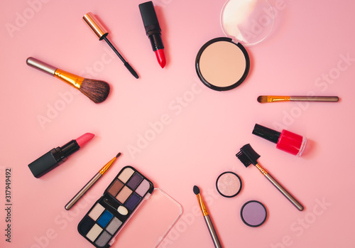 Frame made of makeup cosmetics and brushes on pink background. Top view, copy space.