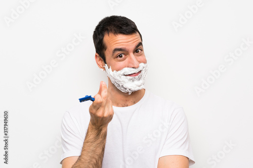 Man shaving his beard over isolated white background making money gesture