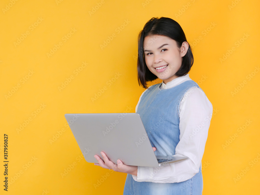 Portrait of an excited young girl holding laptop computer and smilling isolated over yellow background Portrait of an excited young girl holding laptop computer and smilling isolated over yellow background