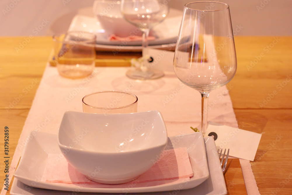 Table setting for two persons with a wine glass with a tag and a pink napkin Table setting for two persons with a wine glass with a tag and a pink napkin