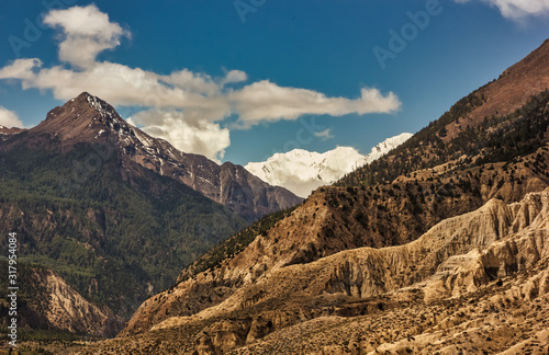 The rugged hilly landscape of the high, snow covered mountains on the Annapurna Circuit trekking trail in the Nepal Himalaya.