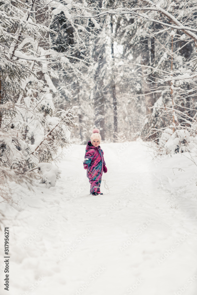 little girl two to three years in pink overalls stands on the background of a winter forest little girl two to three years in pink overalls stands on the background of a winter forest