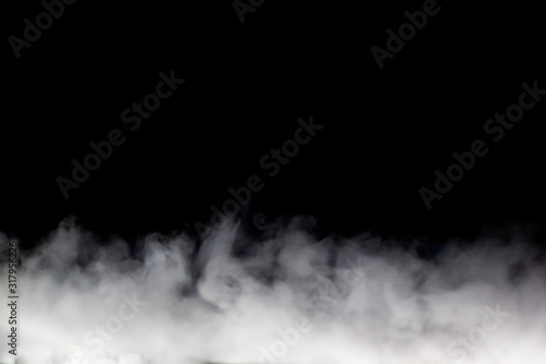 Bright white smoke (fog, vapor) on a dark black background, making up intricate beautiful patterns. A stripe of fog on the bottom edge, the other is darkness