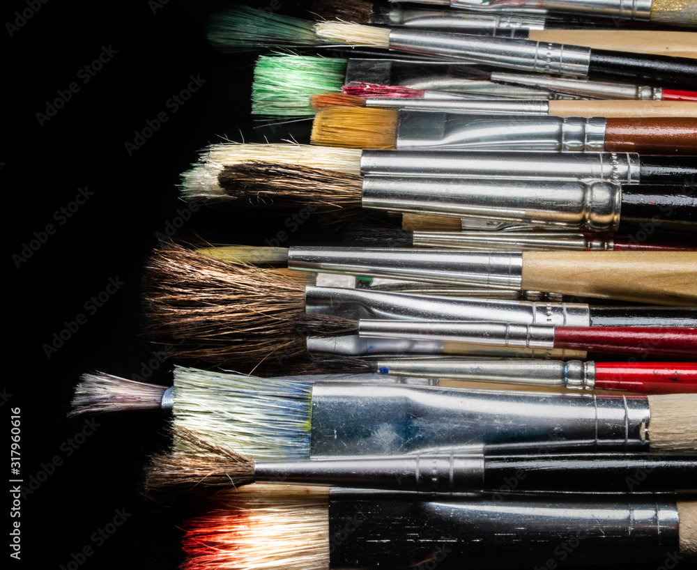 Fototapeta premium different used paint brushes on a black background