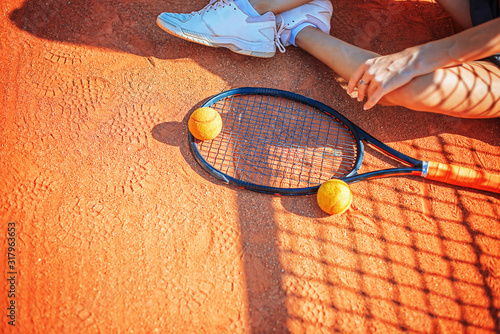 Legs and racket of female player that seets on the ground of the court at daytime. photo