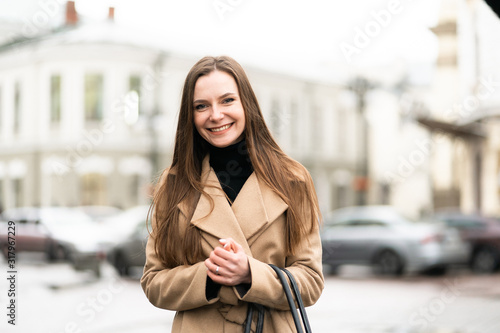 Obraz na płótnie Outdoor fashion portrait of stylish young woman having fun, emotional face , laughing, Urban city street style wearing dark casual trousers, white sweater,creamy coat. and sunglasses Fashion concept. w salonie