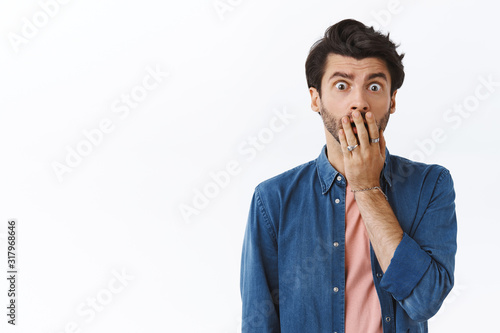 Troubled young bearded man, gasping cover opened mouth, stare worried and concerned, realise something terrible, standing anxious, express compassion as hear friend got in trouble, white background