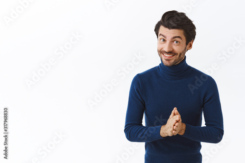 Handsome successful male entrepreneur in blue high neck sweater, rubbing hands and smiling joyfully, feeling deal bring money, suggest customer buy his product, talking with business partners