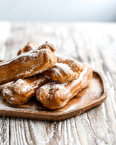 Choux eclairs on wooden plane on a bright rustic background