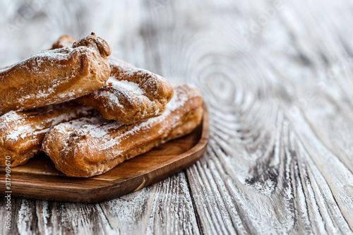 Choux eclairs on wooden plane on a bright rustic background