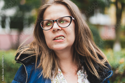 Girl with eyeglasses chewing gum outside