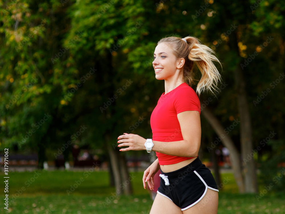 A young girl goes in for sports outdoors. woman in shorts and red t-shirt runs in nature A young girl goes in for sports outdoors. woman in shorts and red t-shirt runs in nature