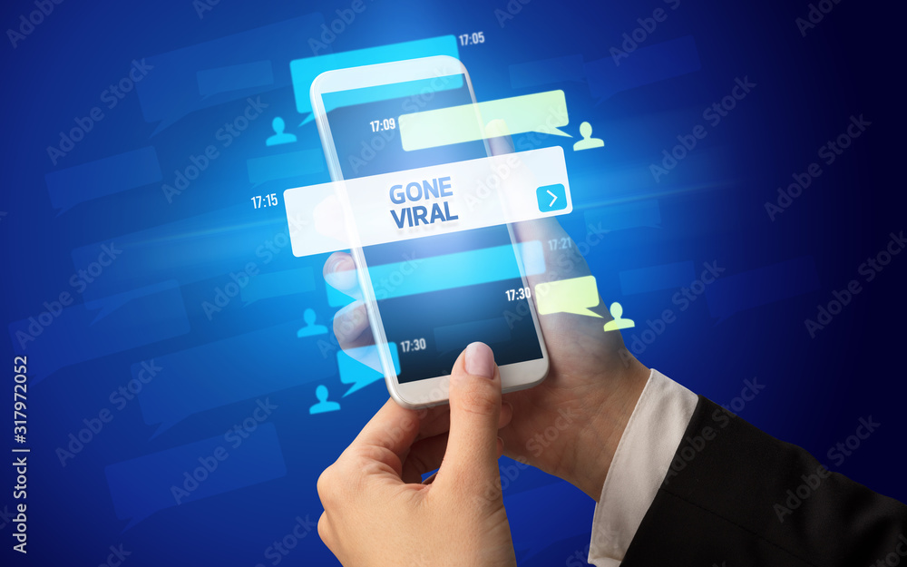 Female hand typing on smartphone with GONE VIRAL inscription, social networking concept Female hand typing on smartphone with GONE VIRAL inscription, social networking concept