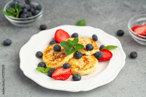 Cottage cheese pancakes or syrniki with blueberry, strawberry and honey. Healthy breakfast.