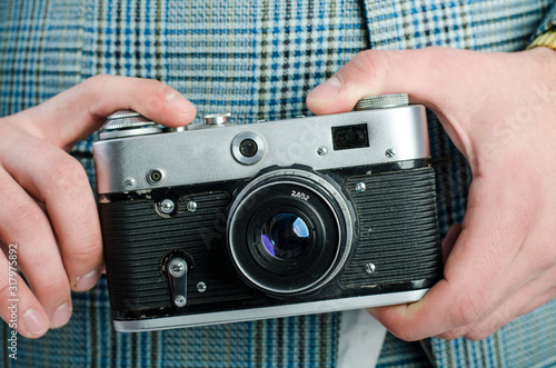 The guy is holding an old camera in his hands. Vintage camera.