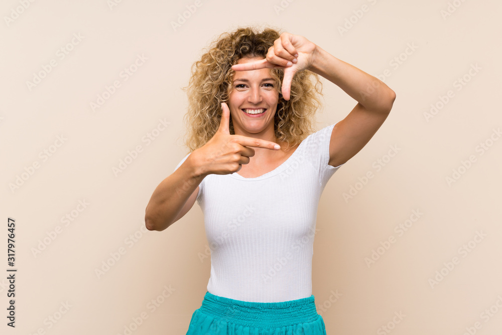 Young blonde woman with curly hair over isolated background focusing face. Framing symbol Young blonde woman with curly hair over isolated background focusing face. Framing symbol