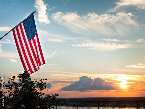 Foto Bright american flag flying above beautiful sunset over Mississippi river