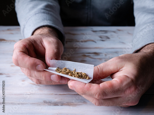 close up look man rolling a marijuana cigar