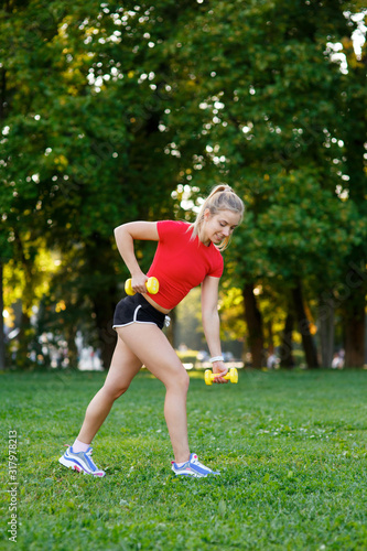 A young woman goes in for sports outdoors. girl with blond hair is training in the park on the nature
