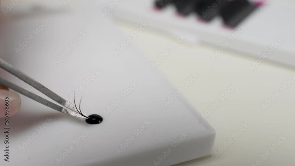 Eyelash Extension Procedure. Close-up of a master at work artificial eyelash extensions material. Hands of the master taking lashes from the set Eyelash Extension Procedure. Close-up of a master at work artificial eyelash extensions material. Hands of the master taking lashes from the set