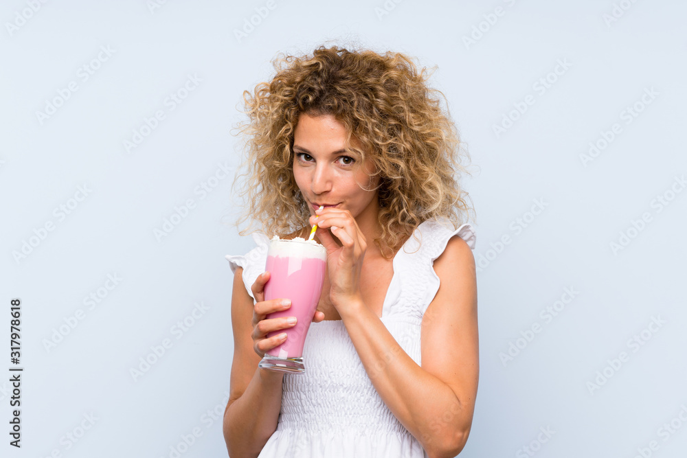 Young blonde woman with curly hair holding a strawberry milkshake Young blonde woman with curly hair holding a strawberry milkshake