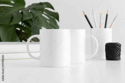Mug mockup with workspace accessories and a monstera plant.