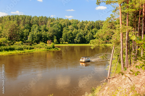 Druskininkai, Lithuania: Tourists are floating on the river in a single-engine pleasure craft. Neman, Nemunas, Nyoman, Niemen or Memel, a major Eastern European river. The view on Nemunas photo