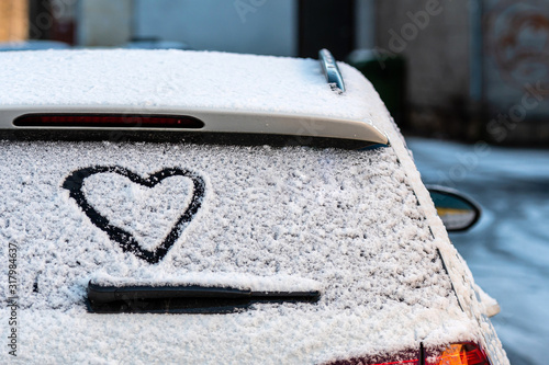 Heart shape on snow covered car rear window