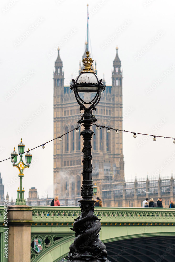 Obraz premium Dolphin lamp standard on Thames Embankment in London at the Westminster Bridge, bloored Westminster Abbey on background