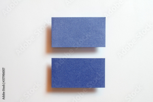 Two blue blank matt linear textured horizontal position business cards flying and isolated on white paper background, us standard size 3.5 x 2 inches, real non professional studio photo.