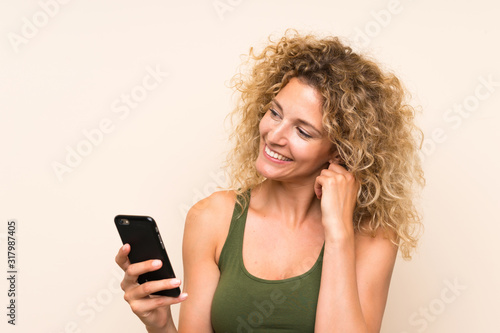 Young blonde woman with curly hair using mobile phone