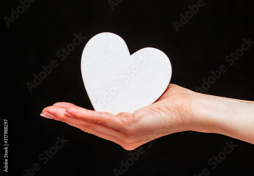 man holds white heart in his hands on the black background