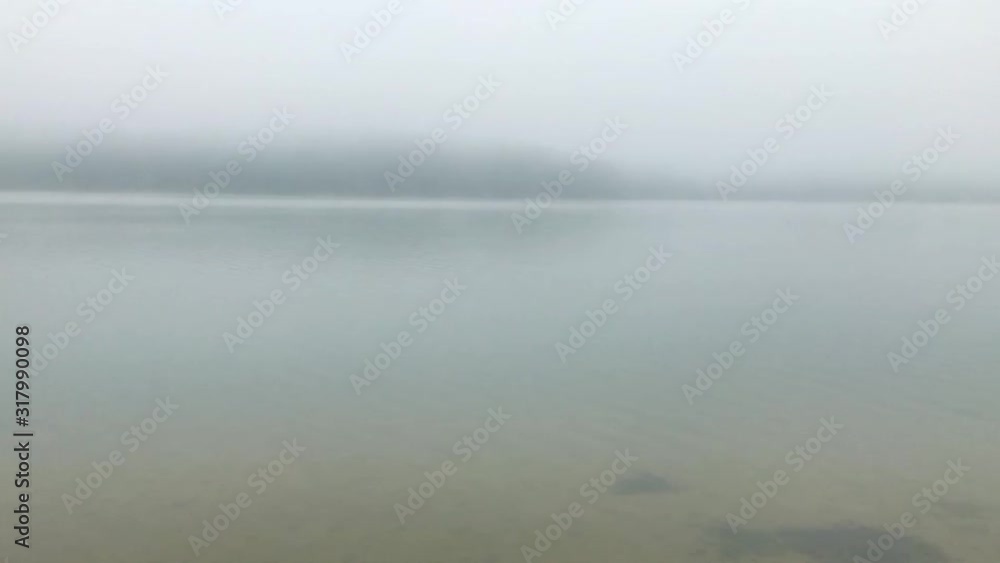 Foggy morning on the lake - waves on the water surface and white fog. Foggy morning on the lake - waves on the water surface and white fog.
